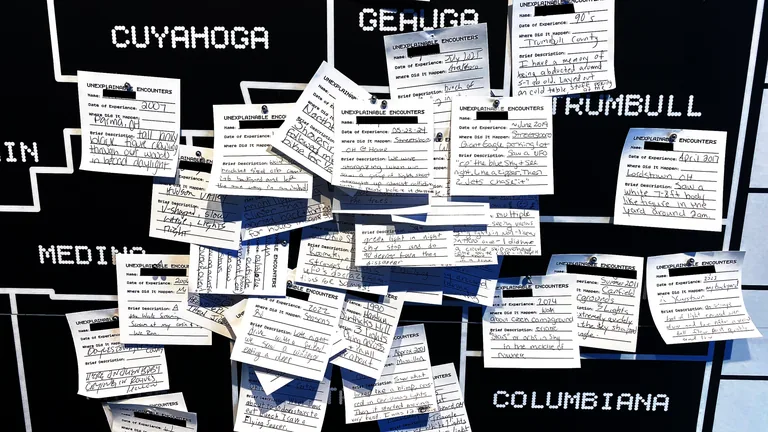 Wall of handwritten visitor encounter cards across Ohio counties at The Mothership