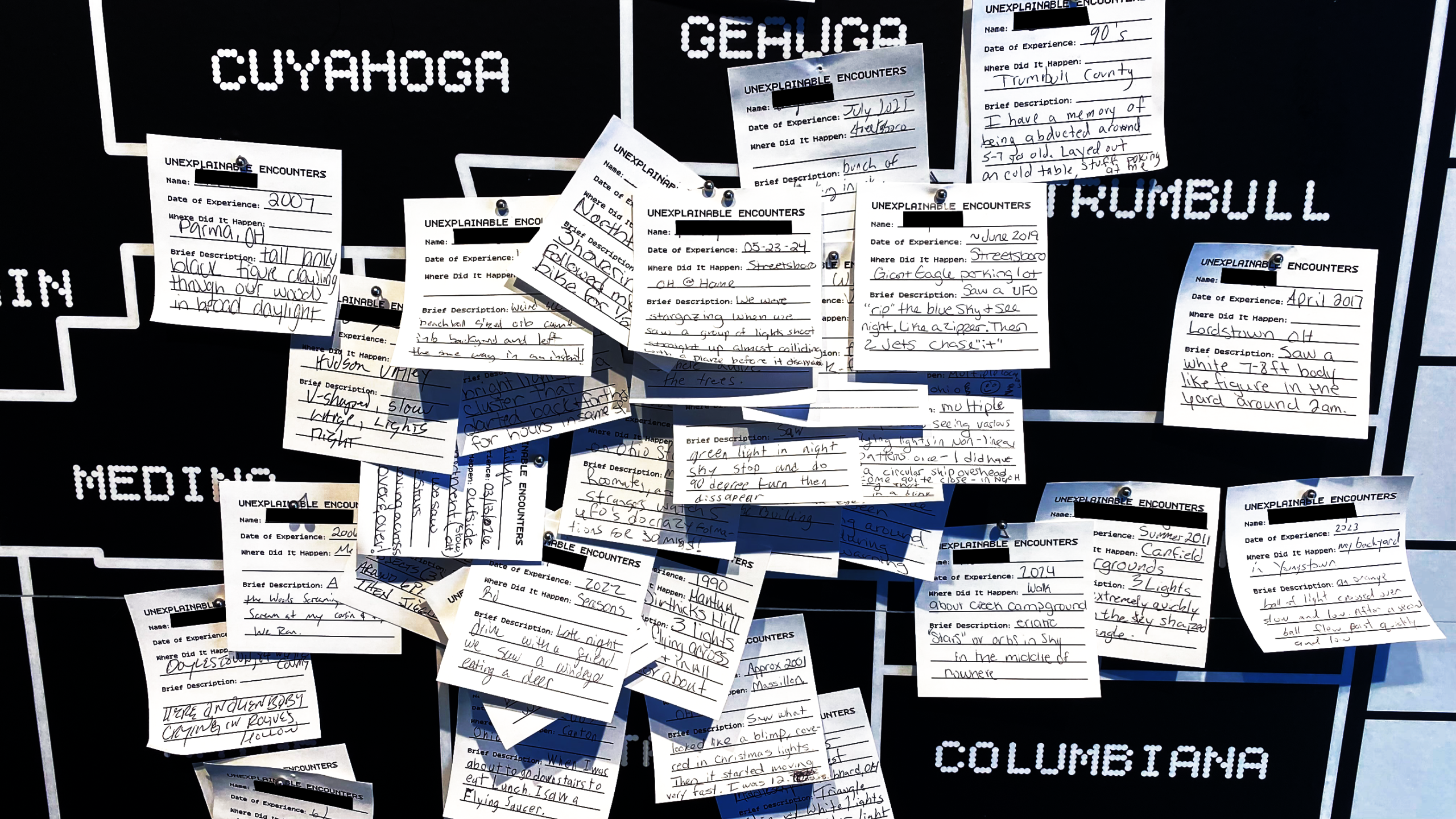 Wall of handwritten visitor encounter cards across Ohio counties at The Mothership